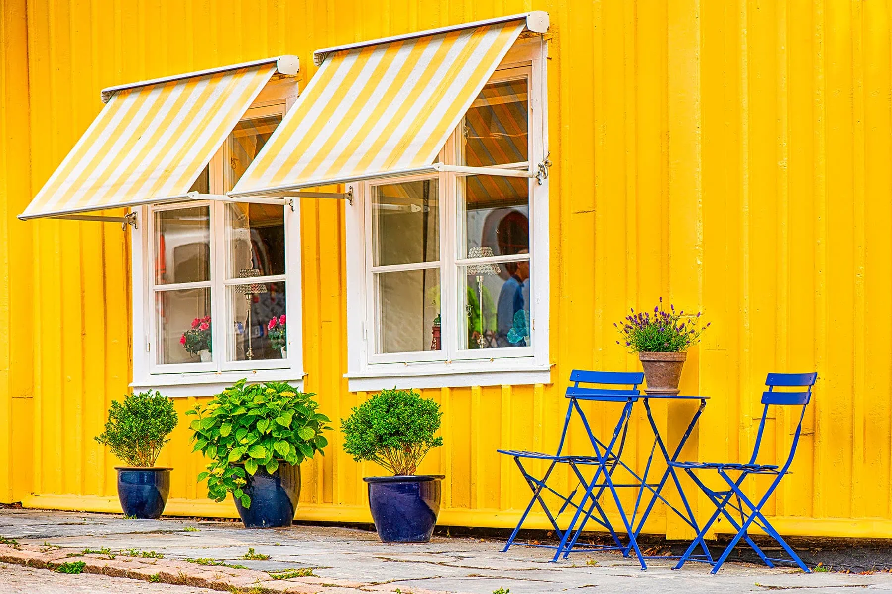 Ett hus i knallgult med blå stolar som är Sveriges färger